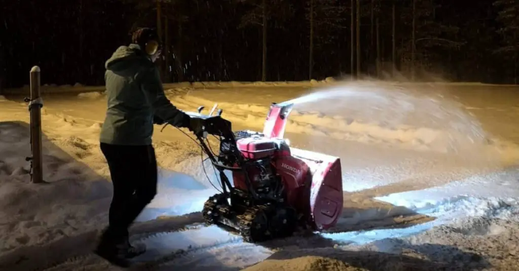 A man with a Snowblower removes snow