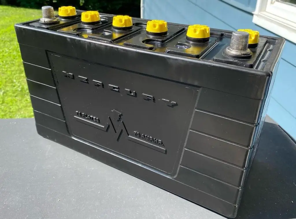 A large black lead-acid battery stands outside