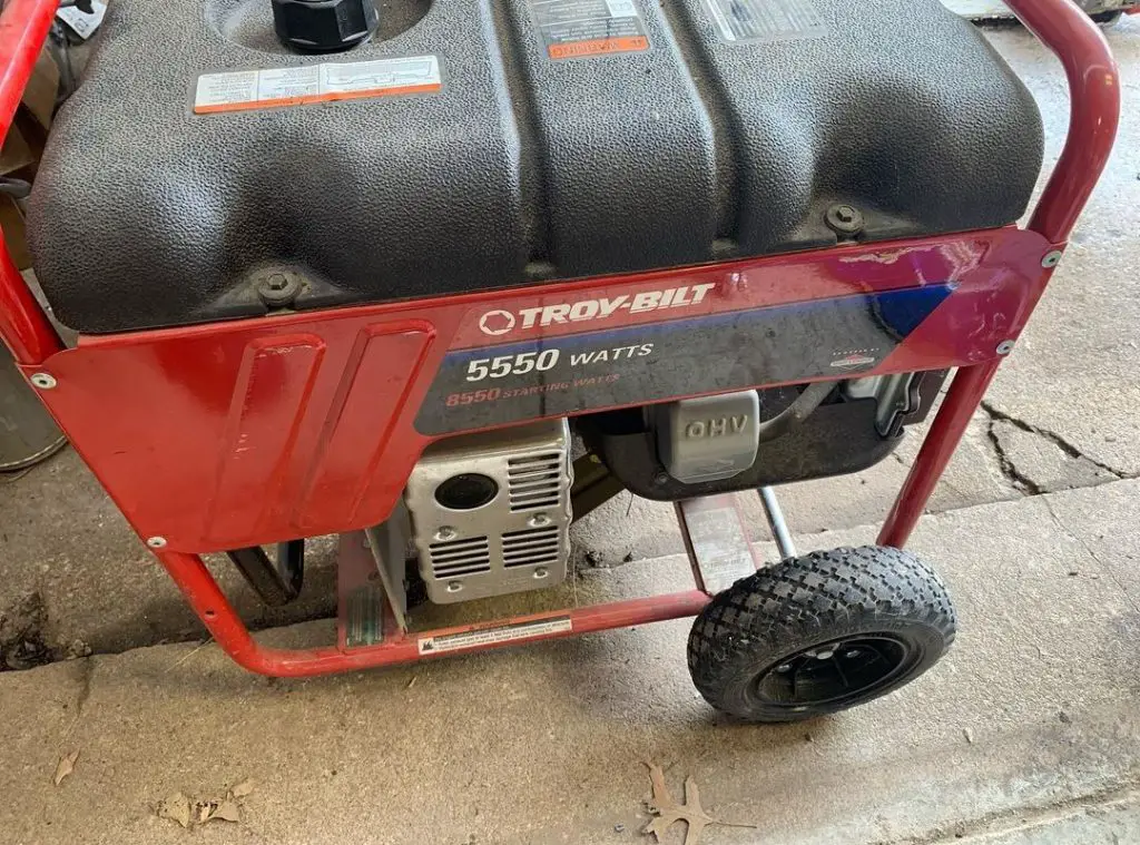 Red portable generator with black wheels on concrete floor