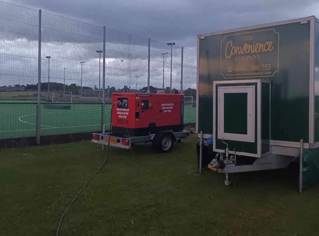 Red stationary generator against the background of the soccer field