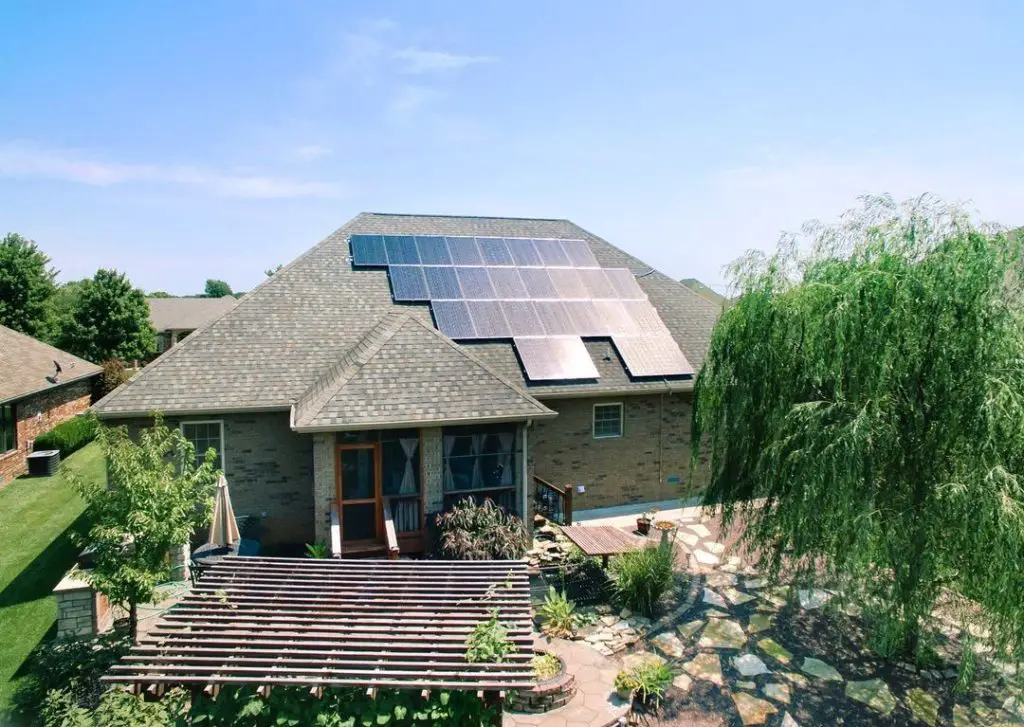 A house with solar panels on the roof against a city backdrop 