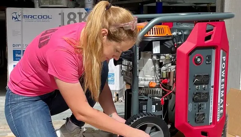 A woman in a pink T-shirt is repairing a generator