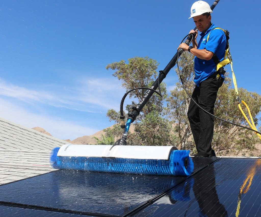 A worker maintains solar panels on the roof