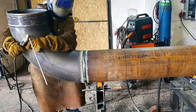 Man uses a stick welder on a pipe